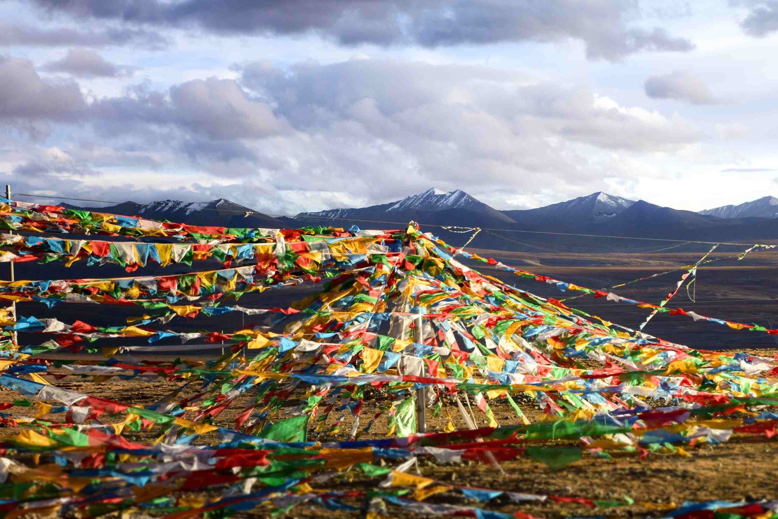 Festivals worth planning around: Vibrant Tibetan prayer flags draped across a rugged Himalayan mountain pass during the holy Saga Dawa festival.